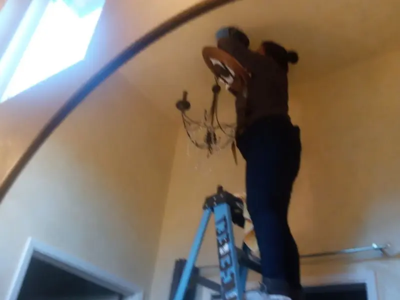 Electrician installing a chandelier in a La Mirada residence